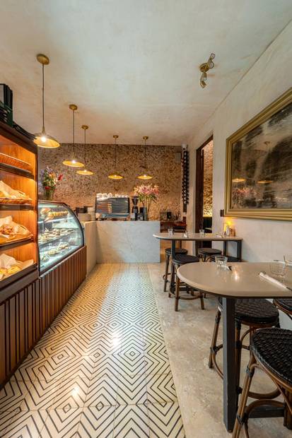 Barra de panadería con vitrina, lámparas colgantes y piso de pasta geométrico