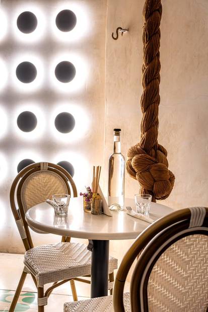 Mesa de mármol junto a un muro de luces circulares y una cuerda anudada
