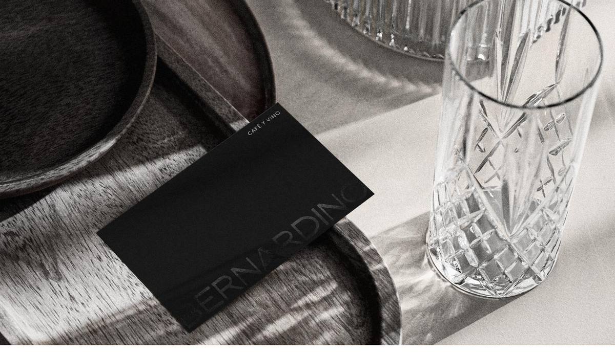 Tarjeta negra junto a un vaso de cristal tallado.